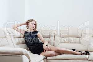 Blonde woman in black dress sitting on sofa