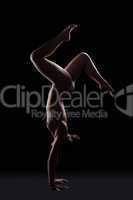 Nude gymnast posing in dark studio on hands