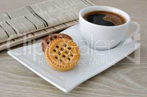 a cup of coffee and biscuits and a newspaper