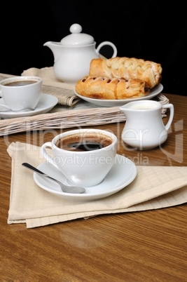 a cup of black coffee with a milkman with a tray of pastries
