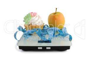 cake and apple on scales measuring tape wrapped