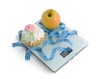 cake and apple on scales measuring tape wrapped