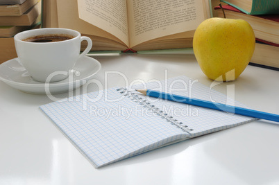 notebook with a pencil on a table with a cup of coffee and an ap