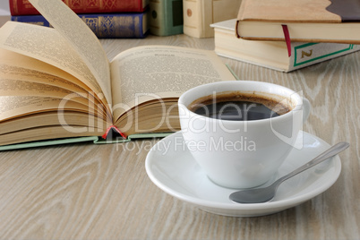 cup of coffee on a table with books.