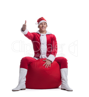 Young man santa claus sit on red bag with presents