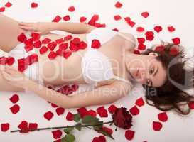 Ein junge Frau von Rosenblättern umgeben