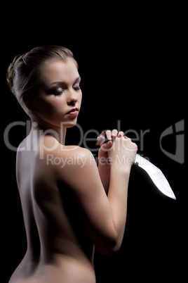 Nude young woman with knife in dark