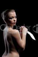 Nude young woman with knife in dark