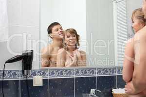 Happy young couple in bathroom smile before mirror