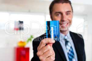 Cheerful businessman holding up his credit card