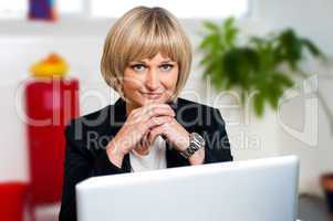 Business executive posing with laptop open at work desk