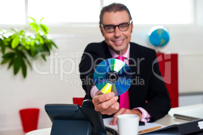 Bespectacled boss presenting a compact disk