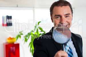 Business executive holding magnifying glass