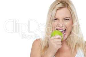 Closeup shot of a blonde woman biting an apple