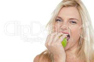 Sexy blonde female eating fresh green apple