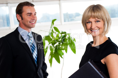 Handsome boss passing by smiling female colleague
