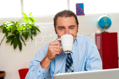 Smiling male manager enjoying hot coffee