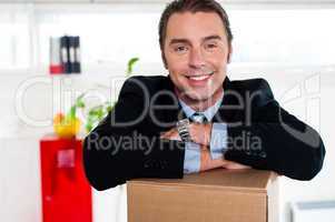 Handsome businessman leaning on packed carton