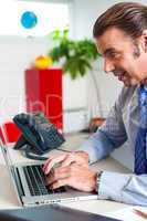 Businessman typing report on a laptop