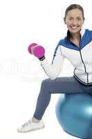 Cheerful woman seated on pilates ball and exercising
