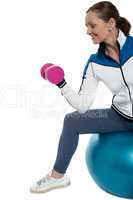 Woman on swiss ball working out with dumbbells