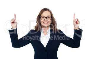 Smiling corporate woman pointing upwards