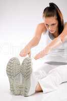Young Caucasian woman stretching towards her feet
