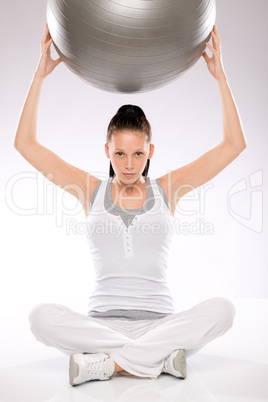 Woman holding fitness ball above her head