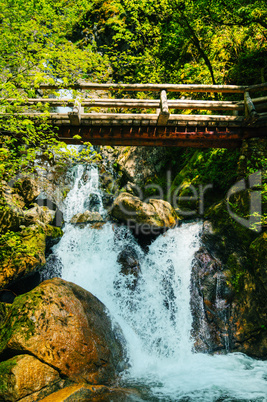 Wooden bridge over waterfalls in the mountains