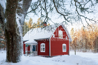 Rot gestrichenes Schwedenhaus in Winterlandschaft in Småland, Schweden