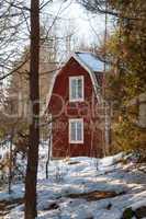 Red painted Swedish wooden house in a wintry landscape