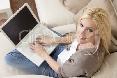 Young Blond Woman Using Laptop Computer At Home on Sofa