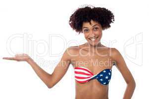 Smiling model in stars and stripes bikini presenting copy space