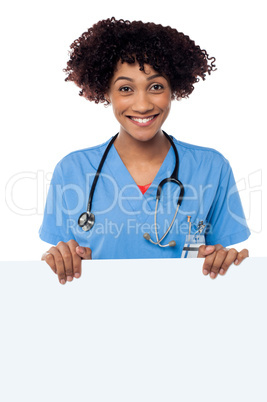 Joyous female doctor standing behind ad board