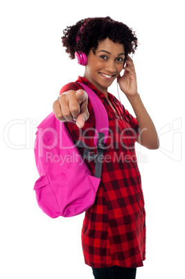 Student with headphones on indicating towards you