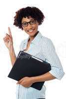 Young secretary holding file and pointing upwards
