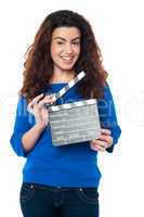 Cute woman in blue attire holding clapperboard