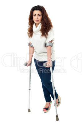 Sad faced woman limping with crutches