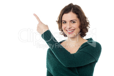 Charming woman pointing towards copy space area