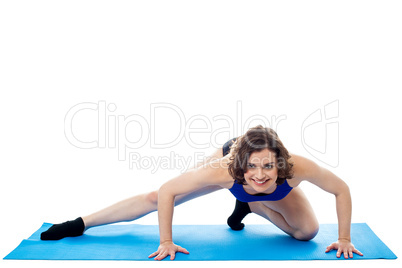 Fit woman crouching on blue mat, studio shot