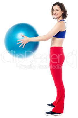 Fit woman posing with big blue exercising ball