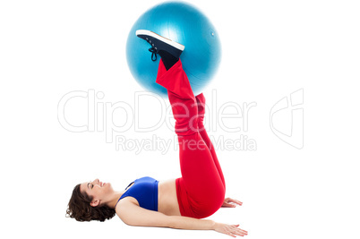 Fit woman holding exercise ball between legs