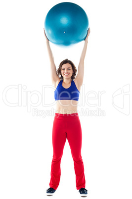 Happy woman lifting pilates ball upwards