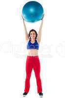 Happy woman lifting pilates ball upwards