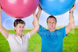 Man and woman holding up exercise ball