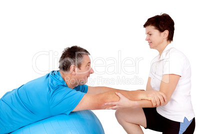 Woman helps man when practicing with the exercise ball