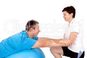 Woman helps man when practicing with the exercise ball