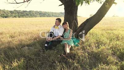 Young couple hugging below the tree on the meadow