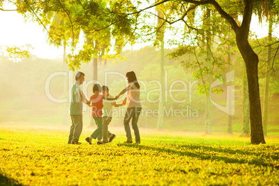 Happy asian family playing on the field