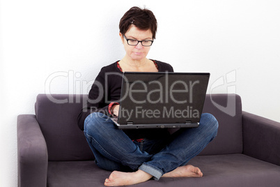 Woman sitting with laptop relaxing on the sofa